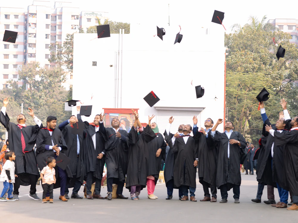 Graduates in caps and gowns celebrating, tossing their caps in the air